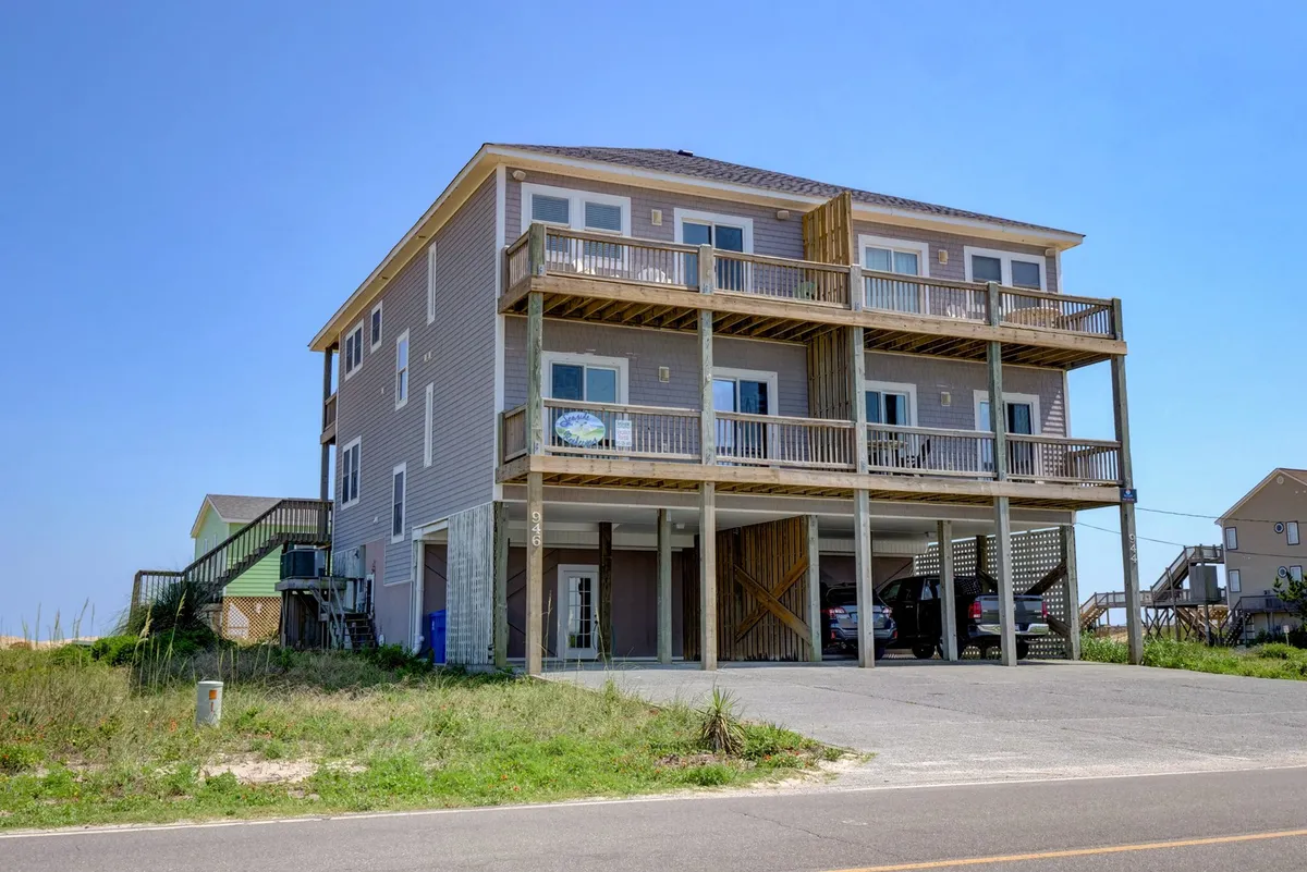 An exterior view of the duplex property with clear sightlines to balconies and surrounding greenery. The house appears inviting, with separate entrances visible, highlighting the private and independent feel of each side of the duplex. The setting suggests both privacy and opportunities to enjoy outdoor relaxation.