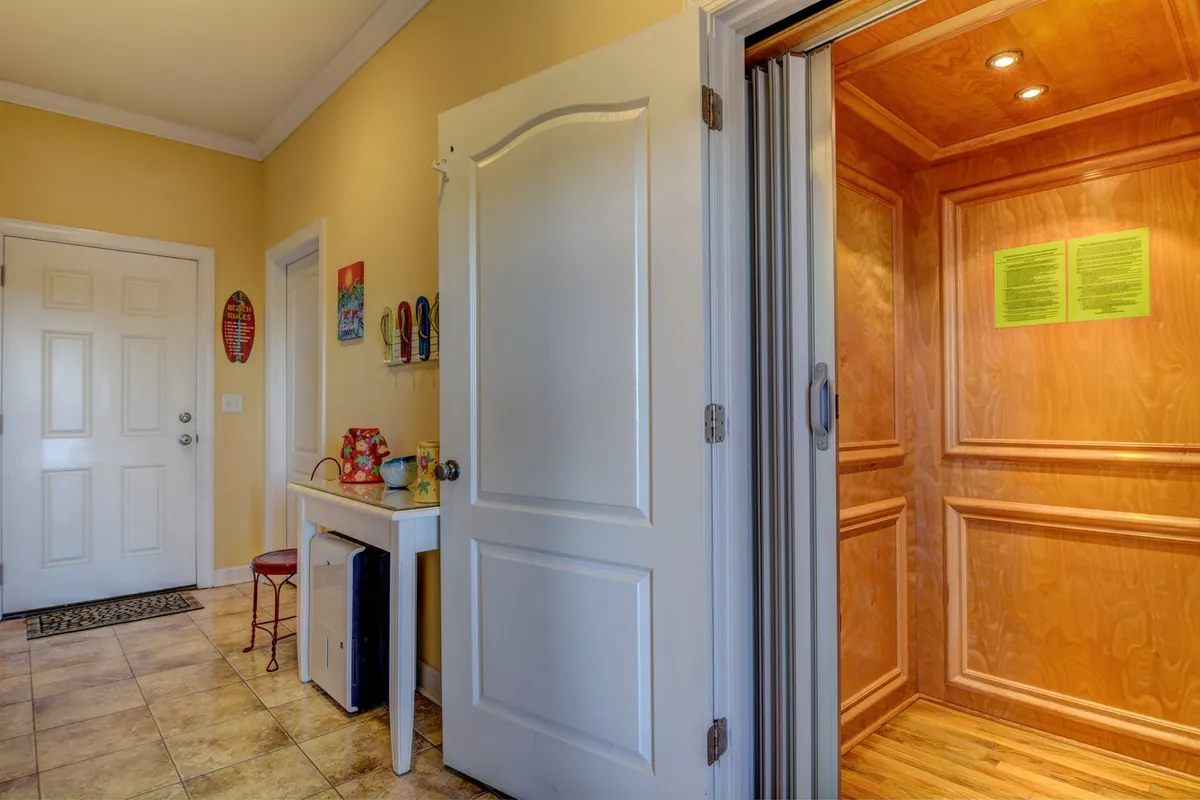 A welcoming interior scene that places the residential elevator near the home's entrance. The elevator is visible with a white door and a small table adorned with decorative items, creating an inviting first impression. This setup emphasizes ease of access, reflecting the home's commitment to convenience for arrivals, mobility, or handling luggage.
